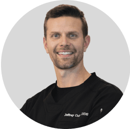 Portrait of a male dentist with a friendly smile, wearing a black professional top
