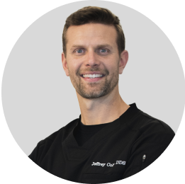Portrait of a male dentist with a friendly smile, wearing a black professional top